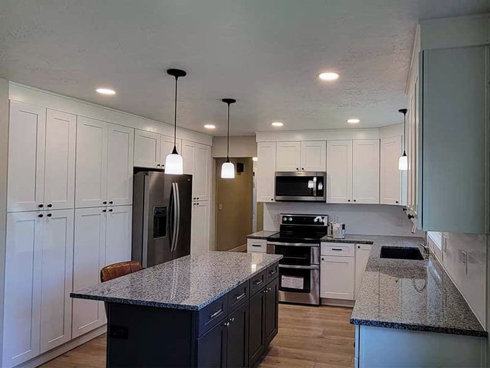 Modern kitchen featuring white cabinetry, granite countertops, and stainless steel appliances.
