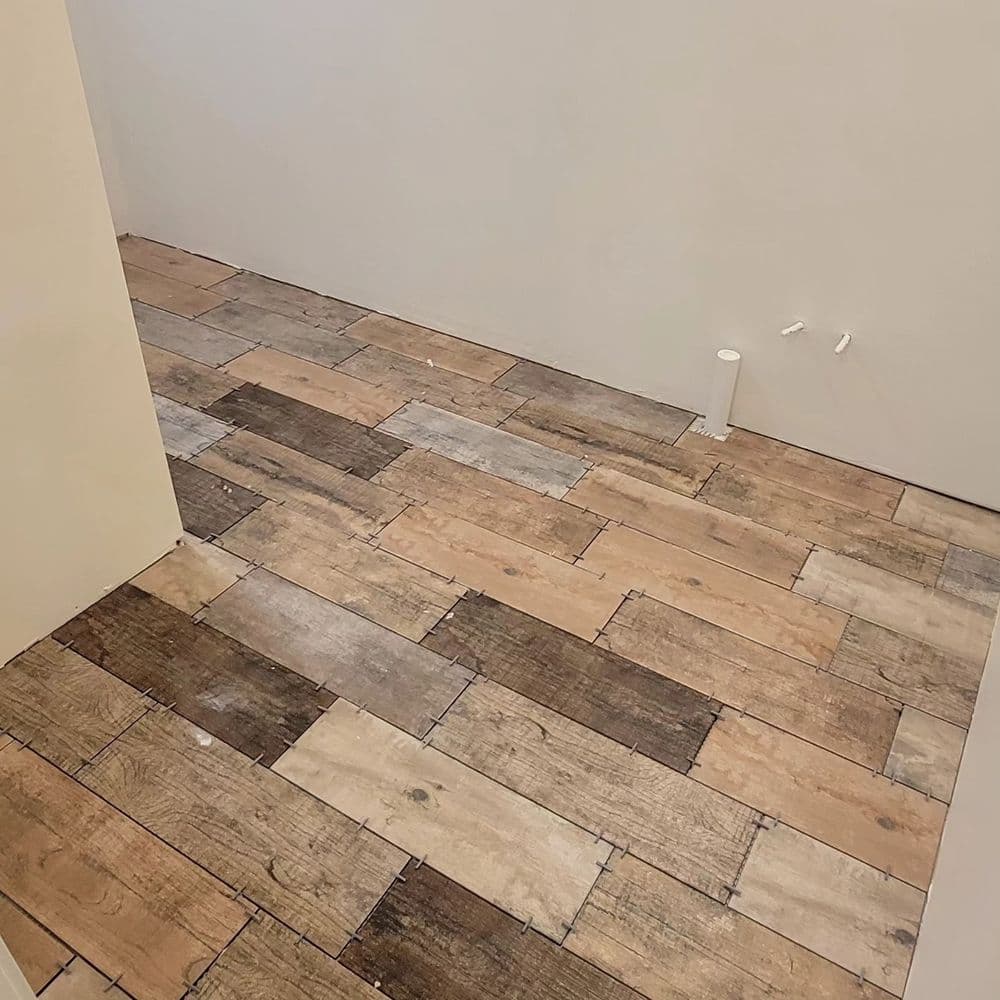 Rustic wooden flooring installation with varying shades, showcased in an empty room.