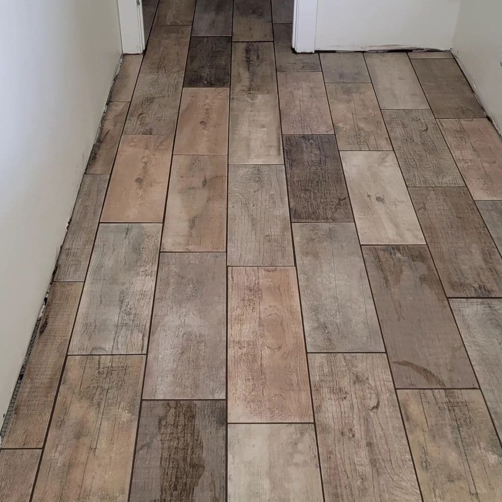 Newly installed wood-look tile flooring in a hallway with a mix of brown and gray tones.