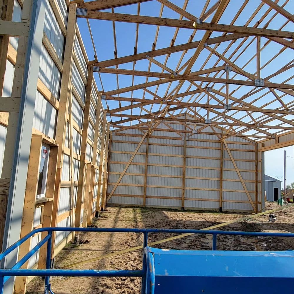 Interior of a wooden-framed barn under construction with exposed beams and open walls.