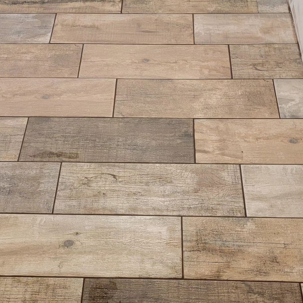 Wood-patterned ceramic tile flooring in varying shades of brown and beige.