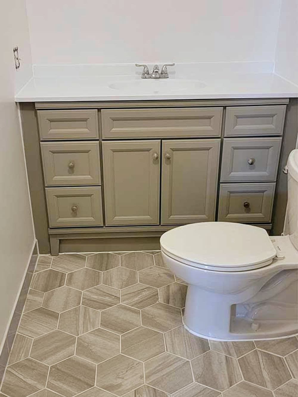 Modern bathroom featuring a gray vanity, white countertop, and stylish hexagon floor tiles.