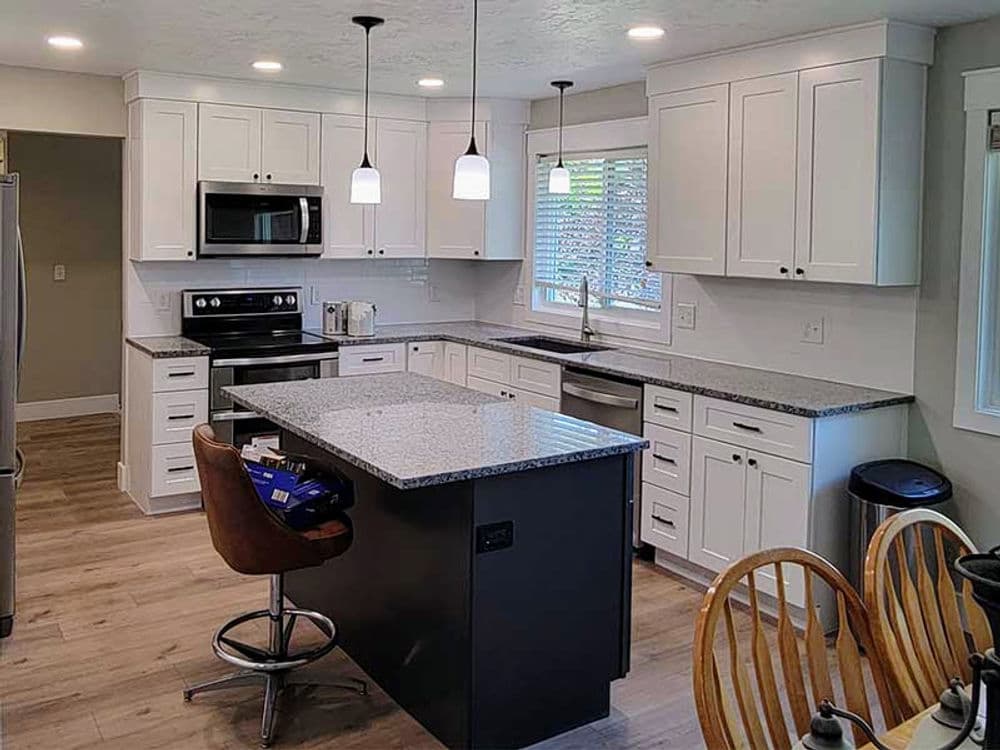 Modern kitchen with white cabinets, granite countertops, and an island with seating.