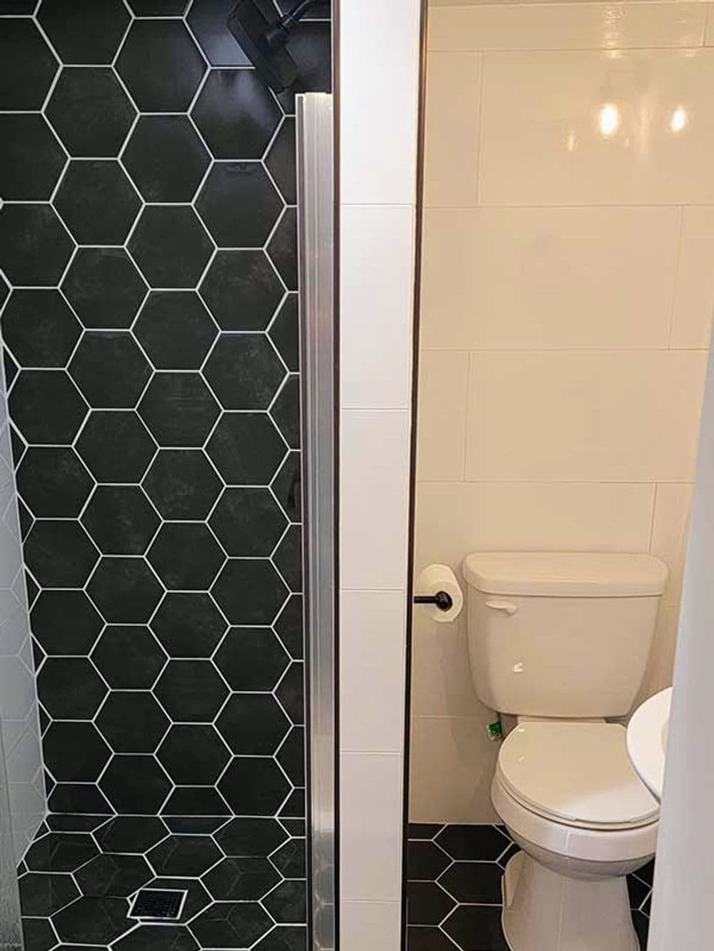 Modern bathroom design featuring hexagonal black and white tile, shower, and toilet.