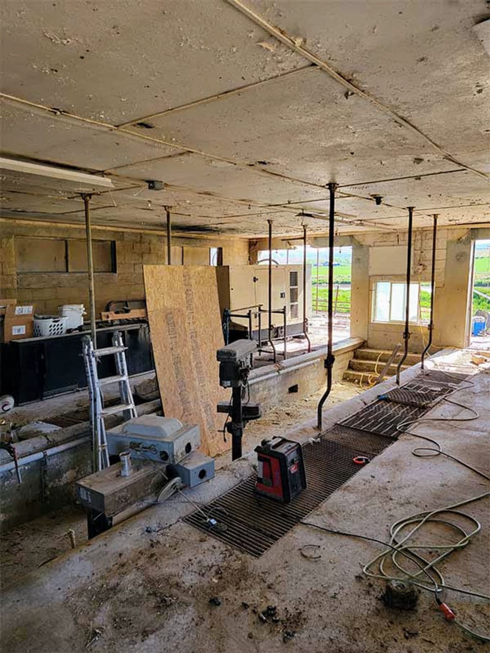 Abandoned interior of a building with construction tools, debris, and exposed structure.