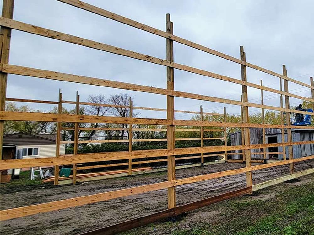 Wooden framework construction process for a large outdoor structure on a cloudy day.