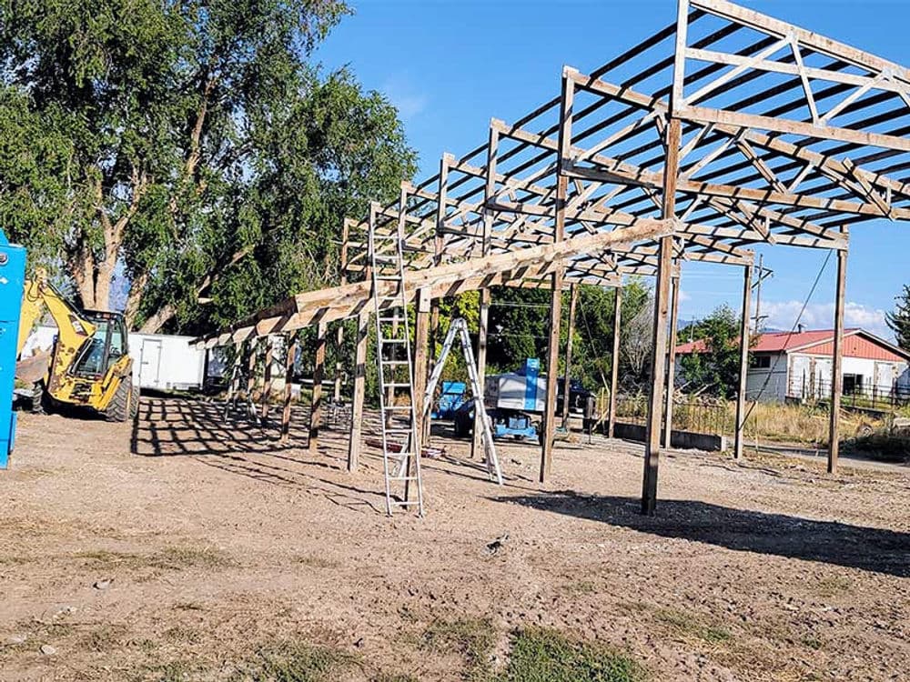 Construction site featuring a wooden structure framework and a ladder against a clear blue sky.