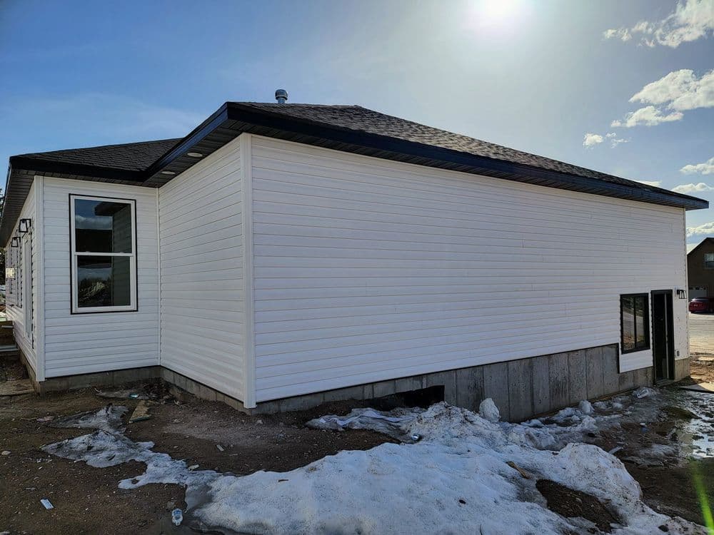 Newly constructed home exterior featuring white siding and clear blue sky in the background.
