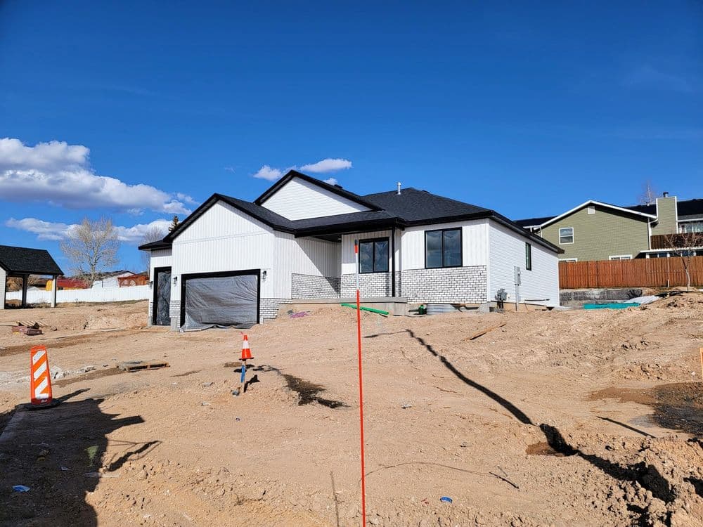 Newly constructed modern home on a sandy lot with clear blue skies in the background.